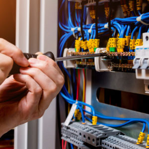 The man is repairing the switchboard voltage with automatic switches. Electrical background