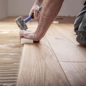 Handwerker verlegt Parkettboden und streicht den Estrich mit Kle Handwerker verlegt Parkettboden und streicht den Estrich mit Kle