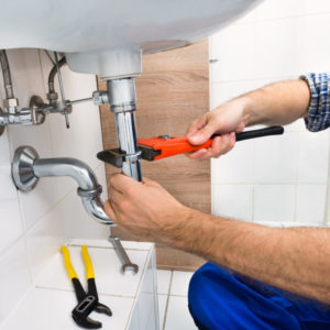 Close-up Of Male Plumber Fixing Sink In Bathroom