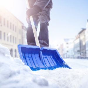Person using a snow shovel on a street in winter